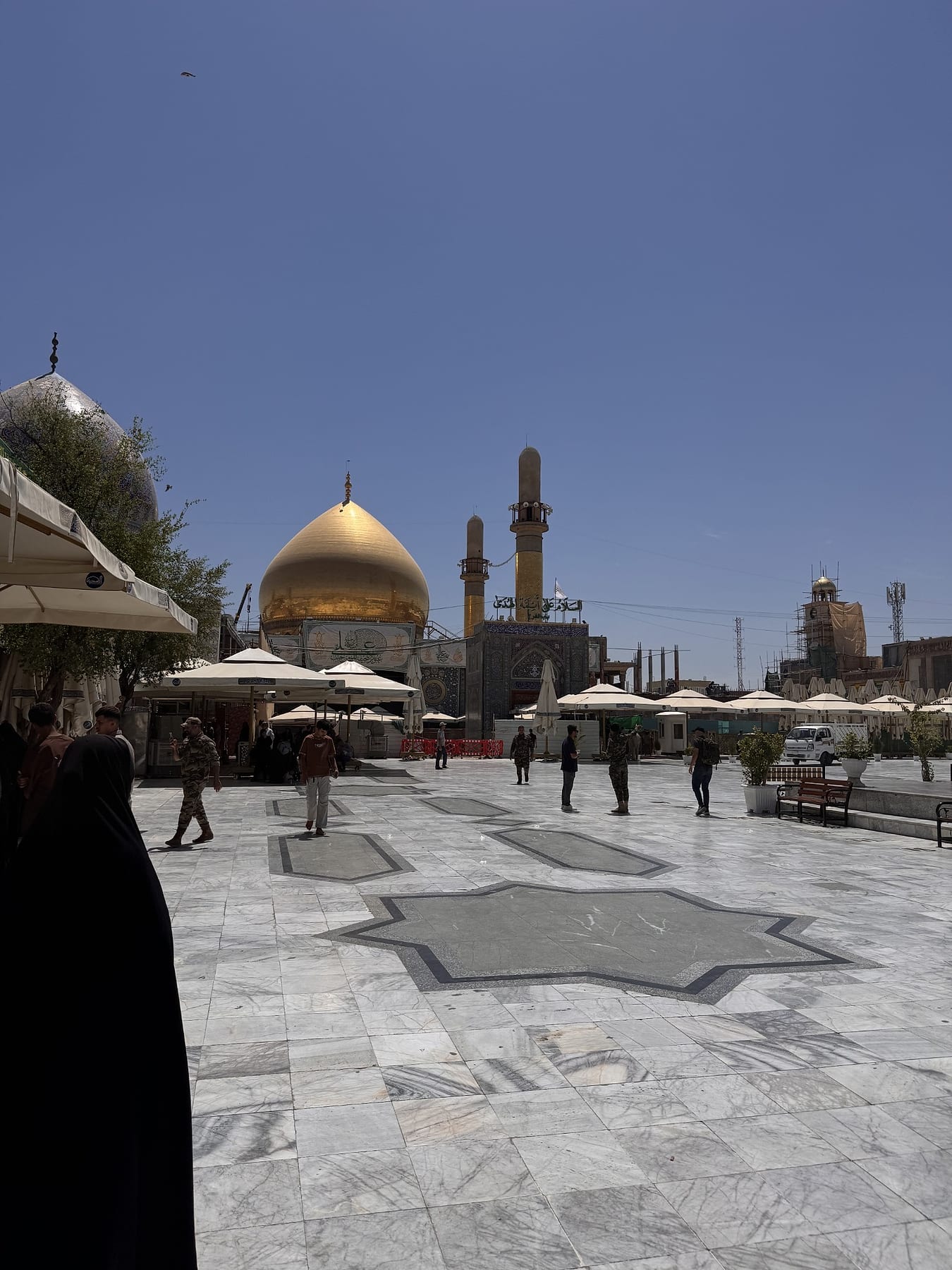 The golden dome seen across a marble courtyard with shade umbrellas, in evening light