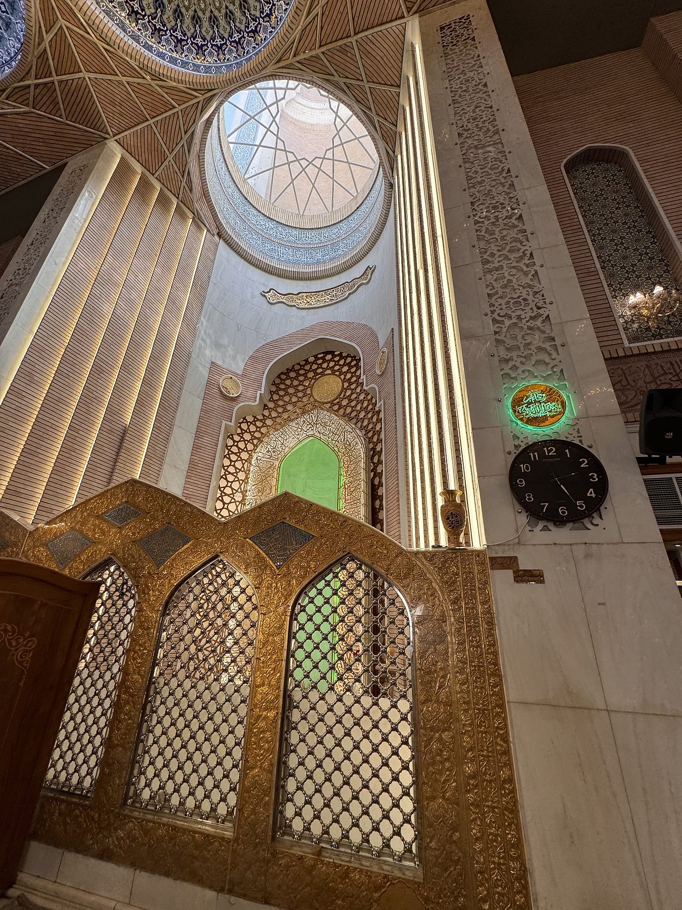 A gilded lattice screen beneath a tall lit niche and a skylight