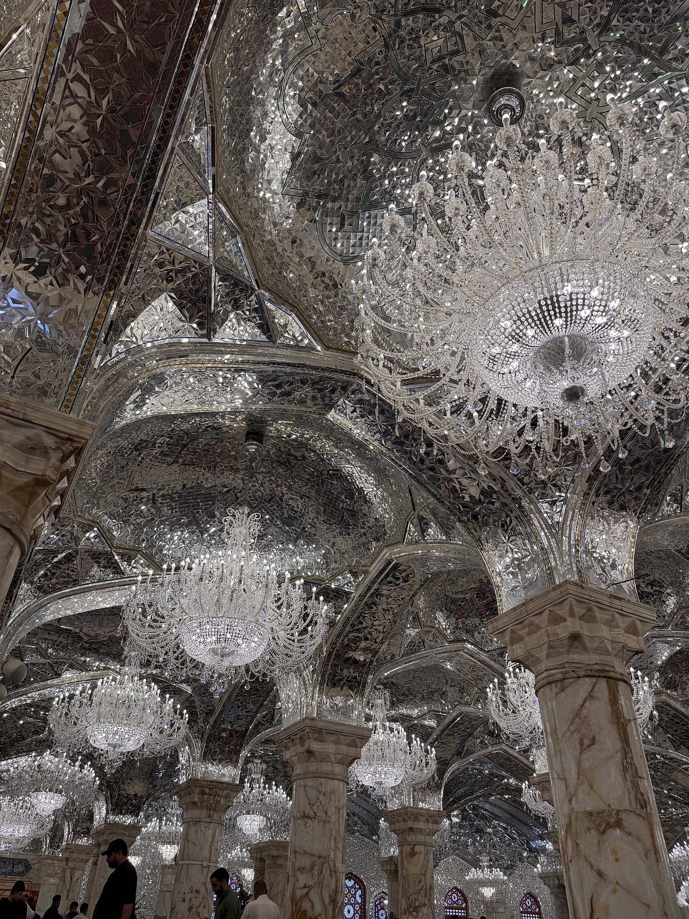 Mirror-work vaulting and crystal chandeliers inside a hall of the shrine