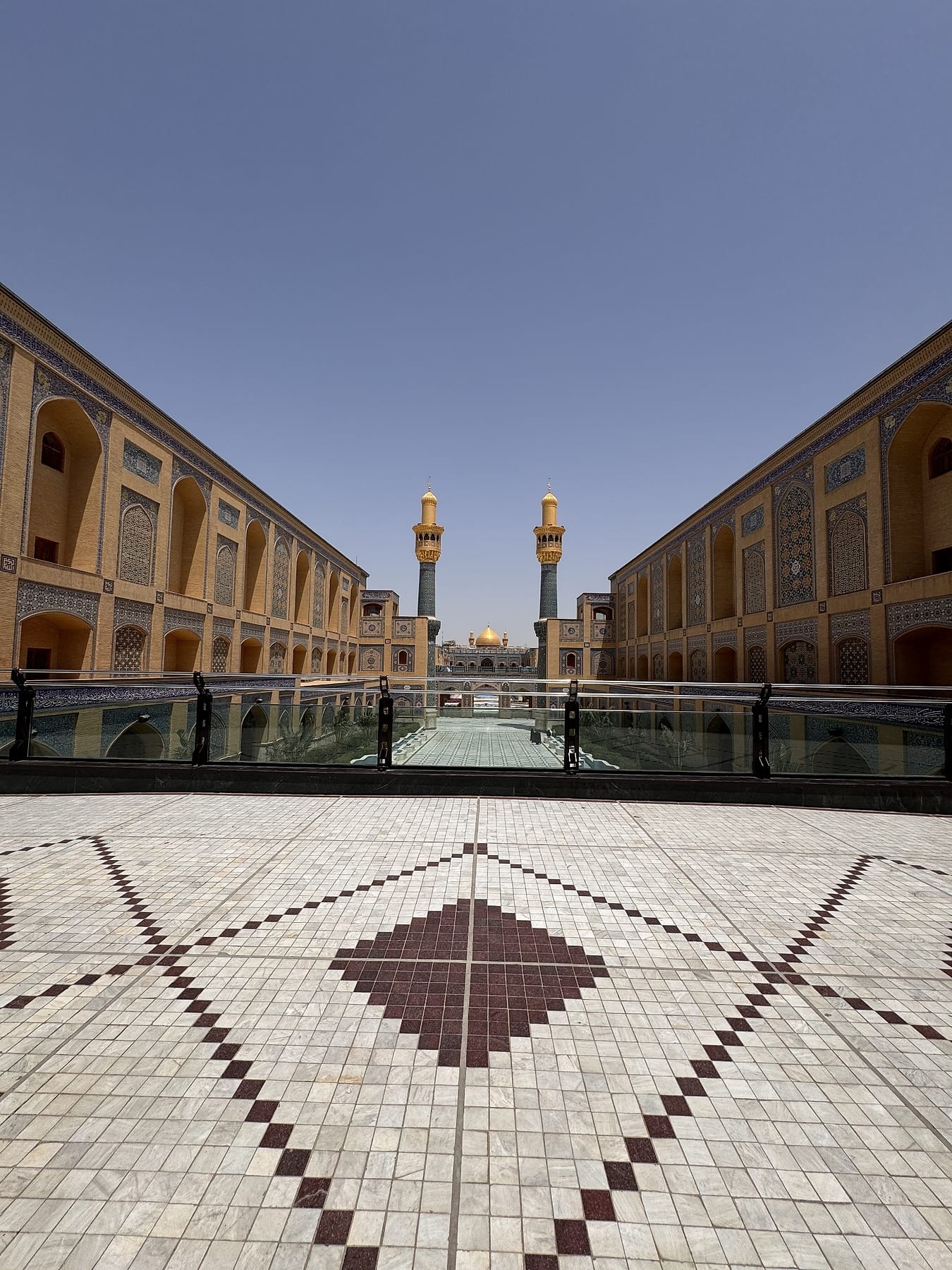 Patterned marble paving in an open courtyard, with the dome and minarets in the distance