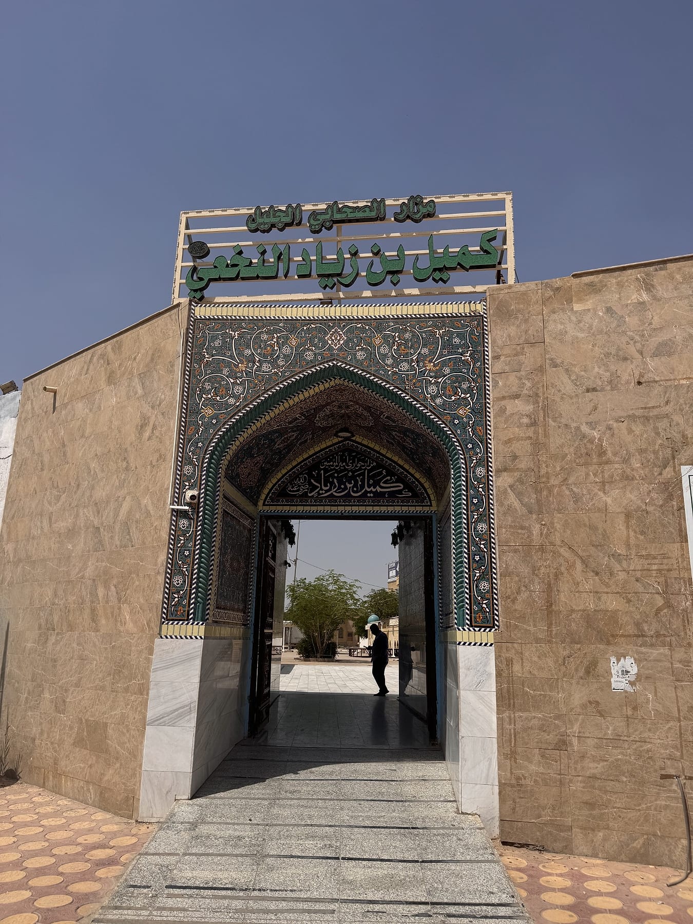 An entrance gateway with a tiled pointed arch and a large Arabic sign above it