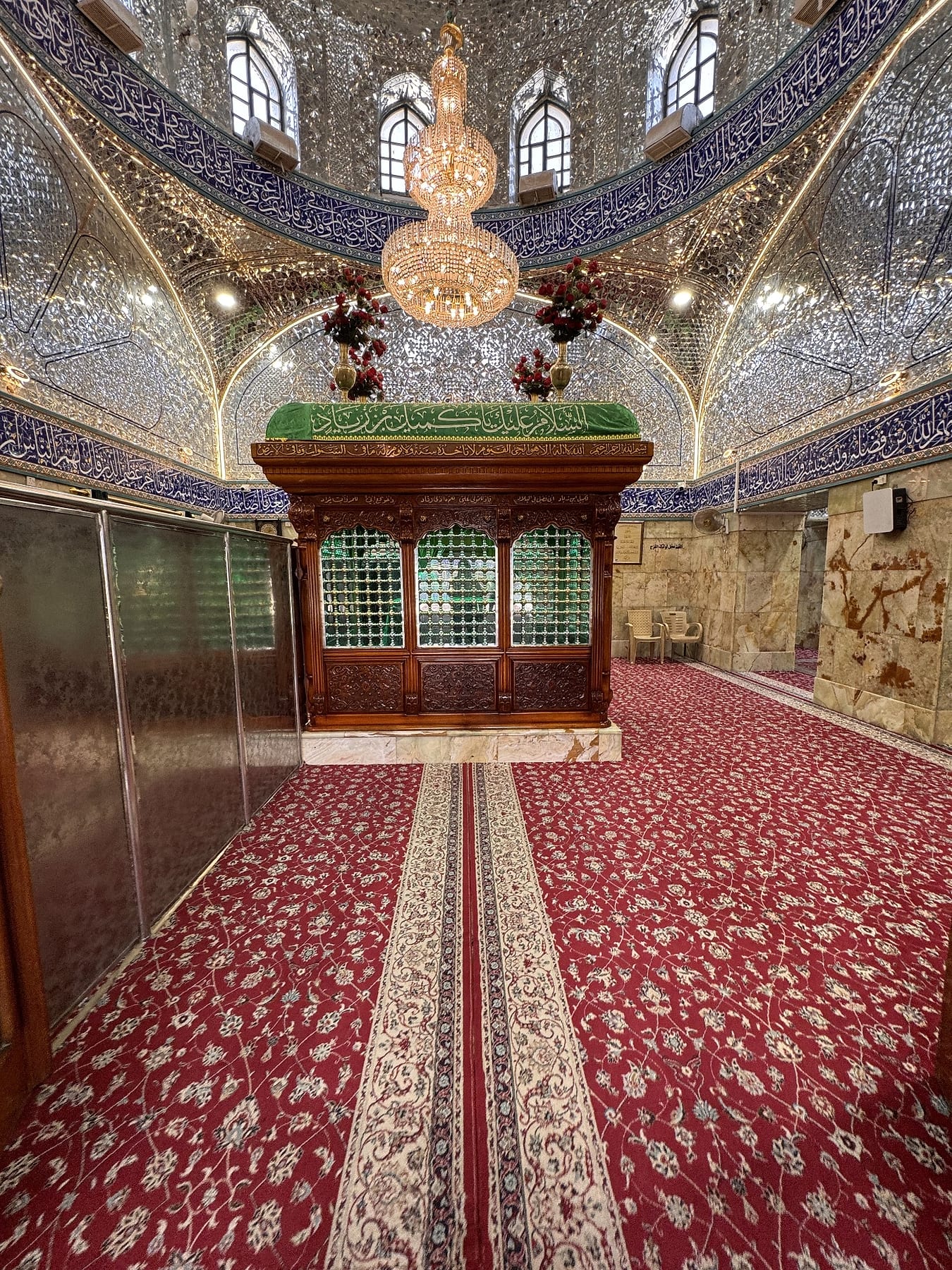 A wooden enclosure with green glass panels under a mirrored ceiling, on red carpet